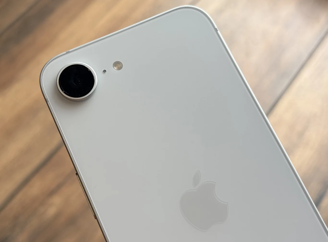 smartfon iPhone 17e ma nieco przestarzały design. biały telefon iPhone z wyraźnym logo Apple, pojedynczym aparatem i lampą błyskową na gładkiej powierzchni