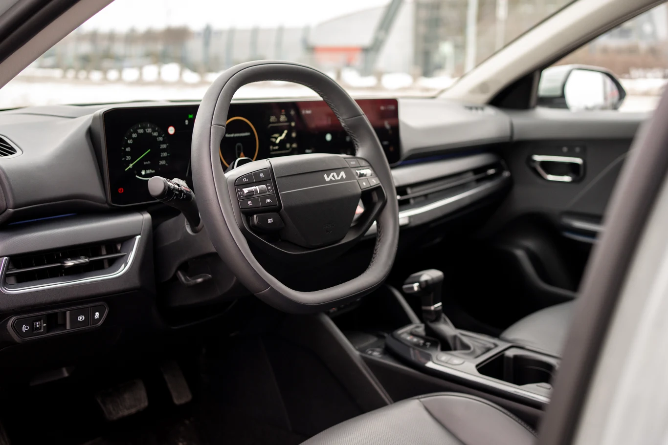 nowoczesna deska rozdzielcza samochodu z cyfrowym wyświetlaczem, wielofunkcyjna kierownica z logo Kia oraz konsola centralna z manualną skrzynią biegów i elementami sterującymi