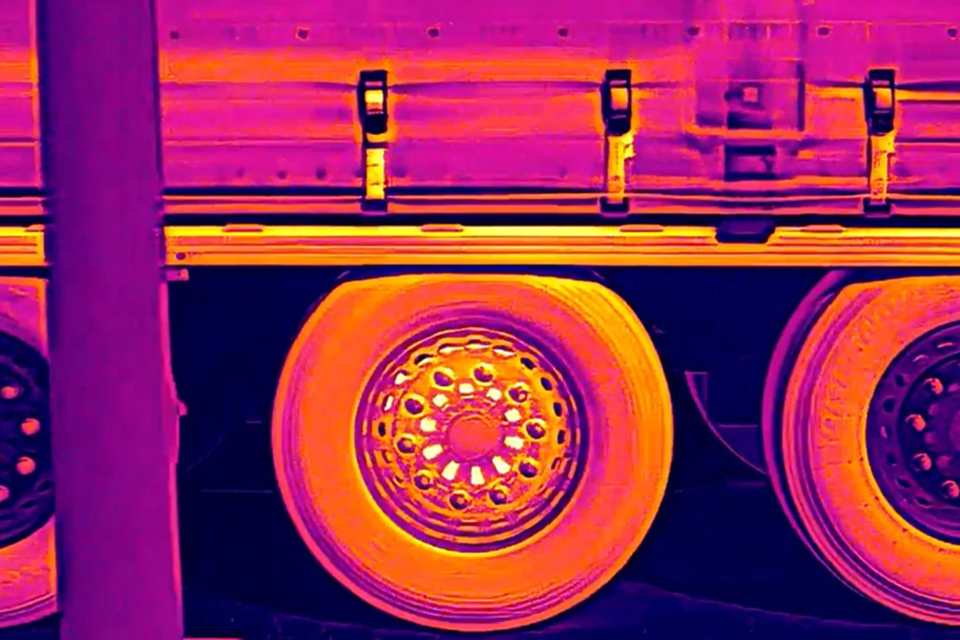 Termowizyjny obraz kół ciężarówki z wyraźnie rozgrzanymi felgami i oponami, ukazujący różnice temperatur na powierzchni pojazdu.