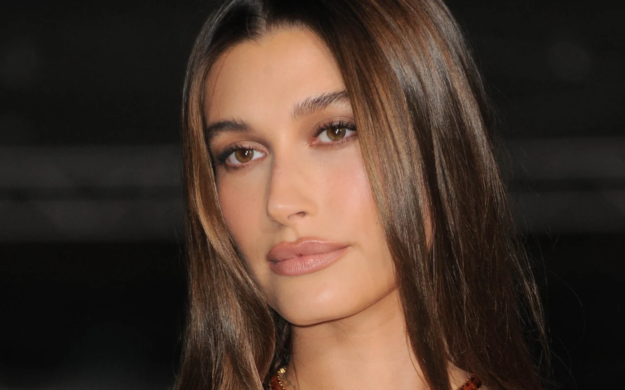 Pomaluj usta w stylu gwiazd młoda kobieta o długich, prostych, brązowych włosach, subtelny makijaż podkreślający oczy i usta, neutralne tło skupiające uwagę na twarzy