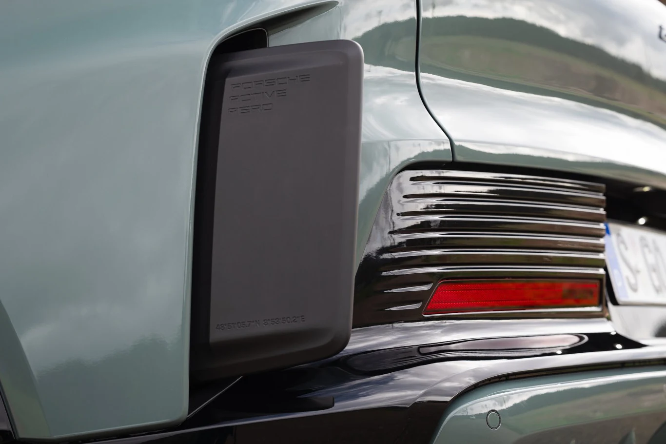 pokrywa portu ładowania z napisem Porsche Electric Drive, nowoczesna tylna lampa LED oraz fragment zielonego nadwozia samochodu