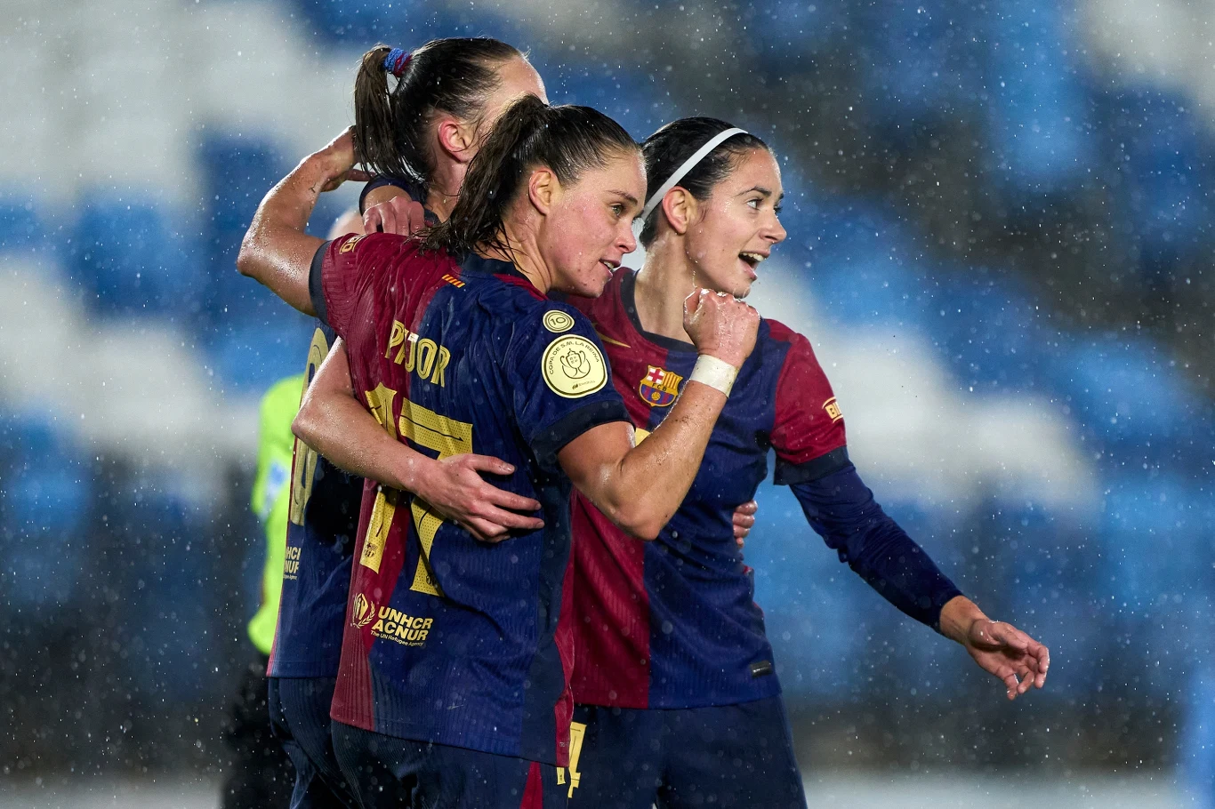 Ewa Pajor, Aitana Bonmati i trzecia piłkarka FC Barcelona na boisku w strojach meczowych, podczas deszczu.