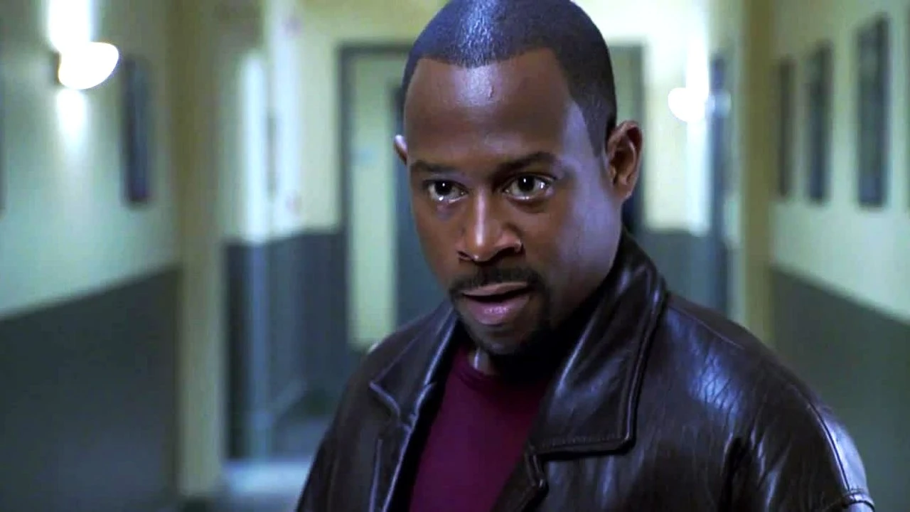 Kadr z filmu "Diamentowa afera" Mężczyzna o poważnym wyrazie twarzy w skórzanej kurtce stoi w wąskim, słabo oświetlonym korytarzu