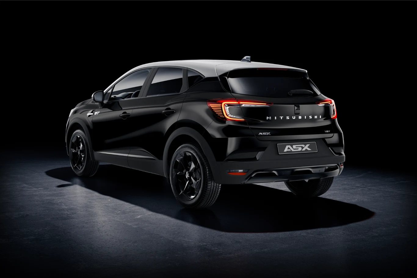 Czarny samochód typu SUV Mitsubishi ASX z przyciemnianymi szybami, nowoczesnym oświetleniem LED i ciemnymi felgami prezentuje się na ciemnym tle podkreślającym sportowy charakter auta.