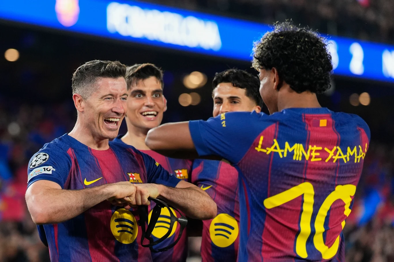 Piłkarze FC Barcelony w granatowo-bordowych koszulkach świętują wspólnie zdobycie bramki, jeden z zawodników z numerem 10 na plecach wykonuje gest, a pozostali są uśmiechnięci i wyraźnie zadowoleni z sukcesu podczas meczu na stadionie.
