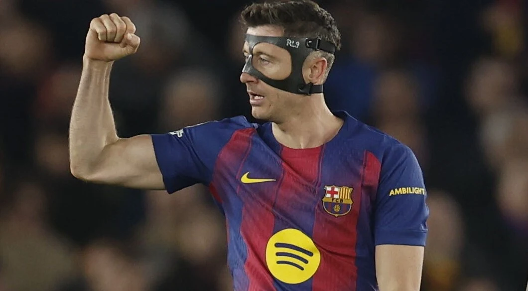 piłkarz w koszulce FC Barcelony i ochronnej masce na twarzy z zaciśniętą pięścią uniesioną w geście triumfu