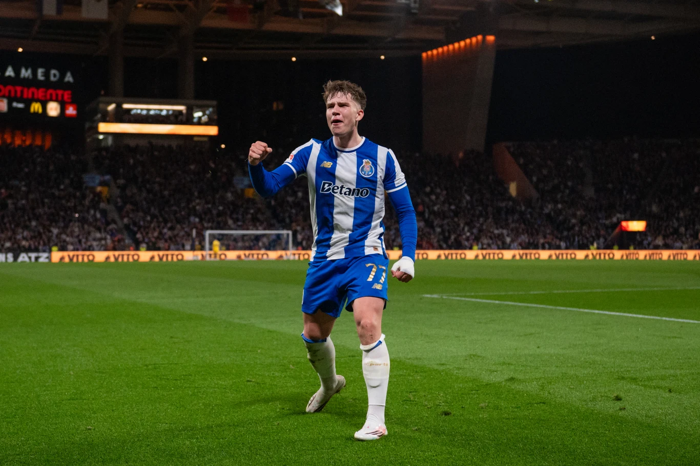 piłkarz w niebiesko-białym stroju FC Porto wykonujący gest triumfu na murawie stadionu podczas meczu, w tle trybuny pełne kibiców