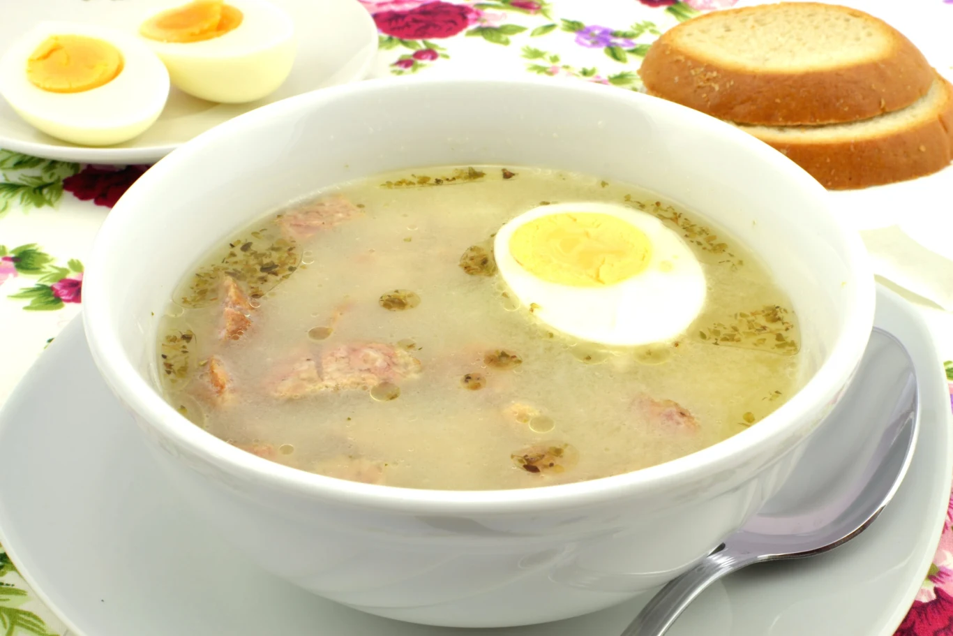 Tradycyjny żurek wielkanocny z dodatkiem kiełbasy i gotowanego jajka Żurek wielkanocny z dodatkiem jajka podany w białej misce.