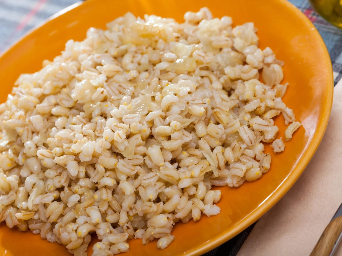 Pęczak możesz ugotować starożytnym sposobem. Porcja ugotowanego pęczaku na pomarańczowym talerzu, przygotowana według starożytnej metody.