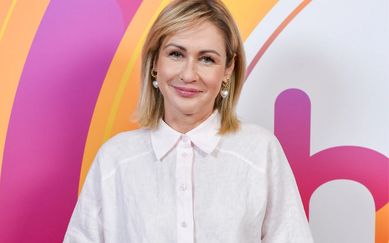 Małgorzata Ohme Małgorzata Ohme w białej koszuli, z perłowymi kolczykami, stoi na kolorowym tle z logo "halo tu polsat".