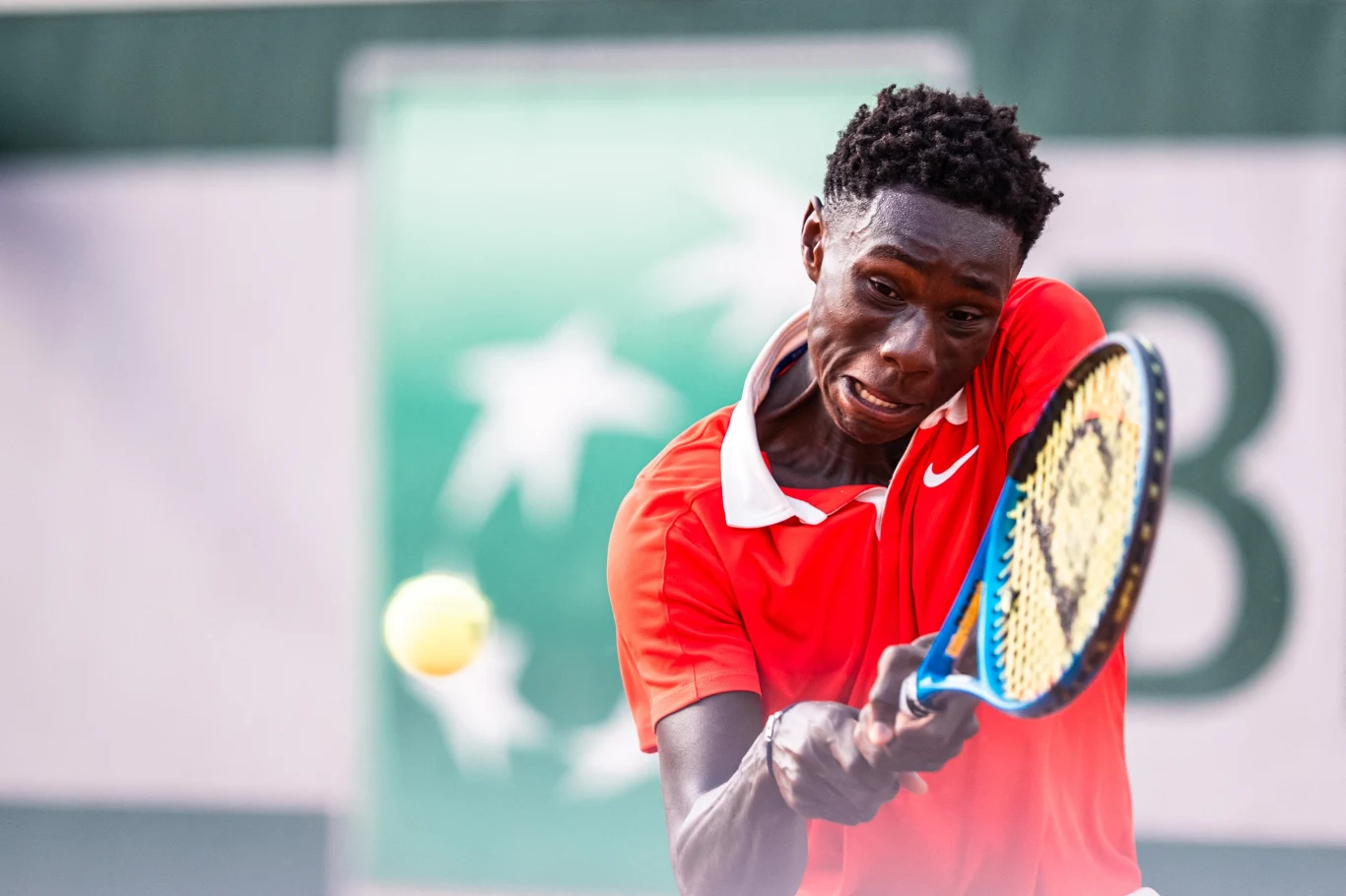 tenisista w czerwonej koszulce uderzający piłkę rakietą podczas intensywnej wymiany na korcie