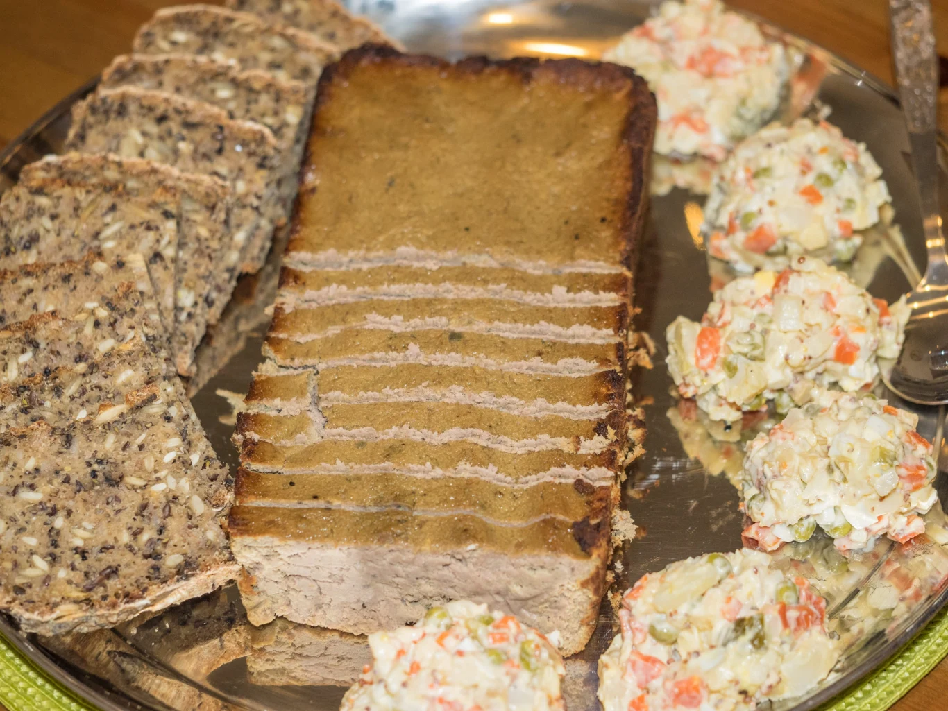 półmisek z pokrojonym pasztetem, ciemnym pieczywem z ziarnami oraz kulkami sałatki jarzynowej ułożonymi wokół