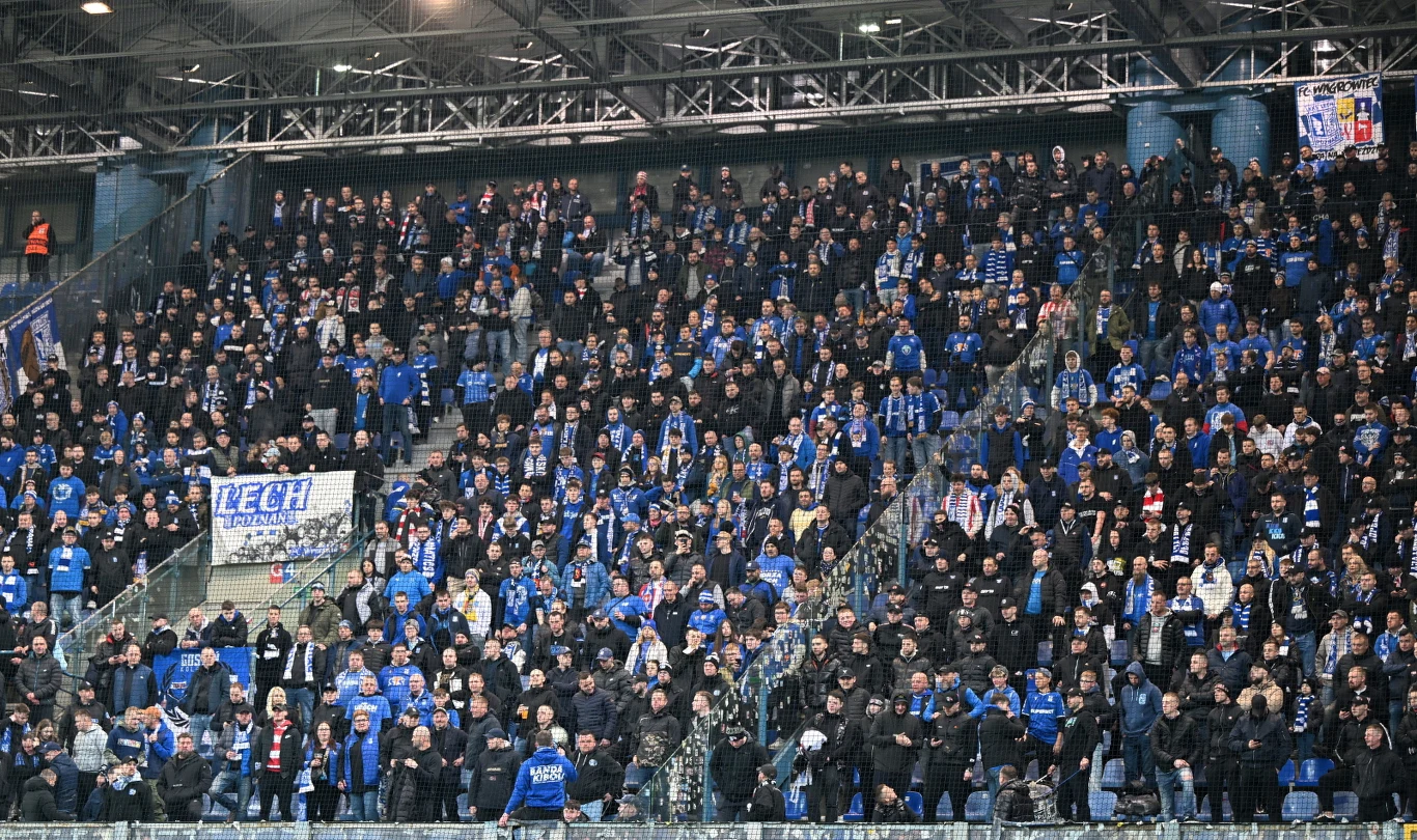gęsto wypełnione trybuny stadionu pełne kibiców ubranych głównie w niebieskie ubrania, wielu z nich trzyma szaliki klubowe i transparenty, atmosfera jest emocjonująca i wspólnotowa