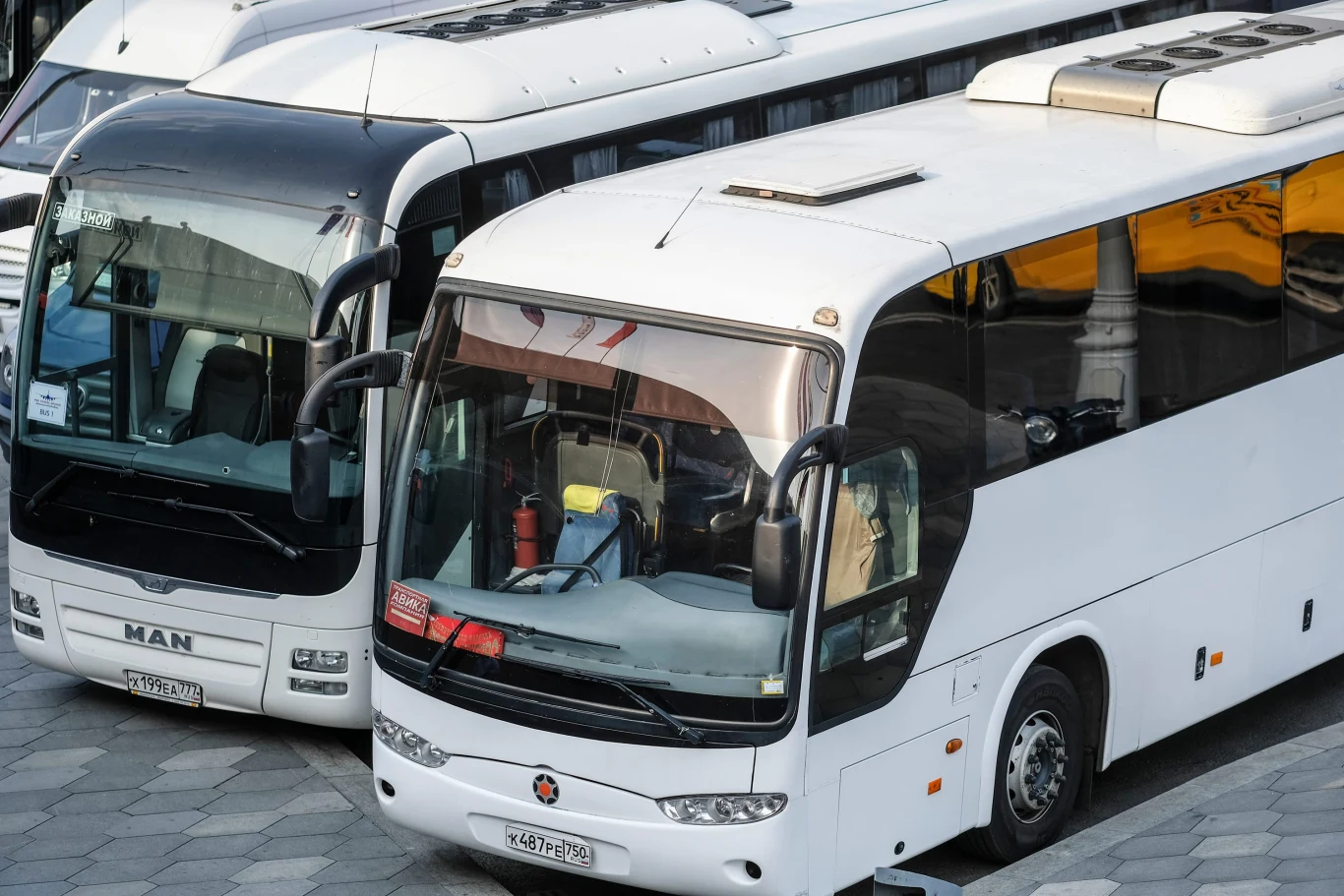 Czy kierowca-zmiennik autokaru może spać w sypialni podczas jazdy? Dwa białe autokary z przyciemnianymi szybami i widocznymi lustrami bocznymi stoją obok siebie na postoju