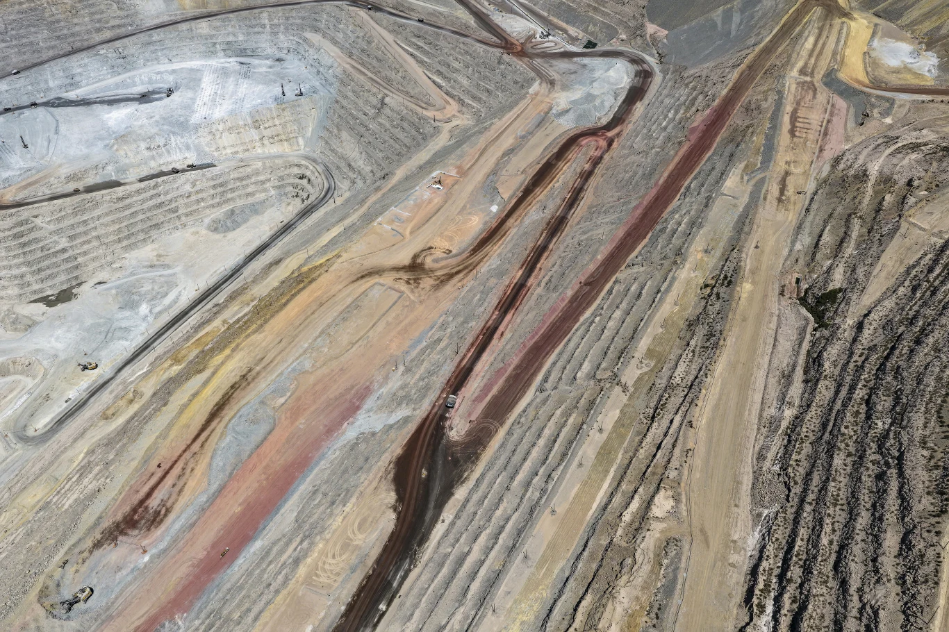 Miedź jest głównie otrzymywana z rud siarczkowych Rozległy teren kopalni odkrywkowej z wyraźnymi poziomymi tarasami, różnokolorowymi warstwami ziemi oraz widocznymi śladami maszyn pracujących na kilku poziomach wydobycia.