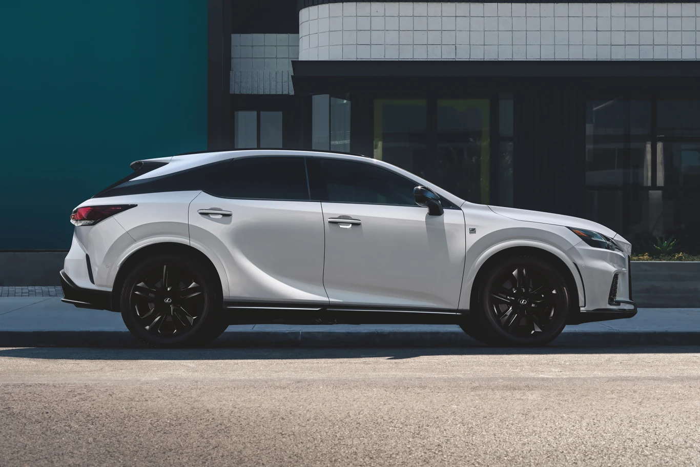 biały SUV o dynamicznej sylwetce i czarnych, sportowych felgach zaparkowany przy nowoczesnym budynku z geometryczną fasadą