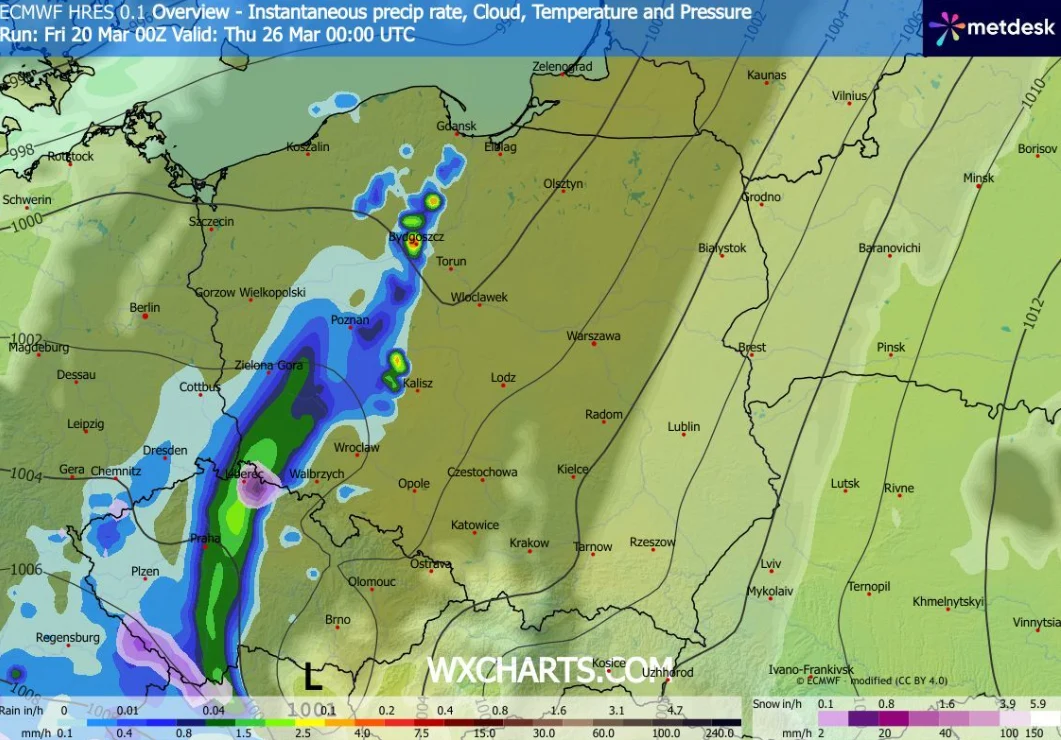 Mapa pogodowa Europy Środkowej z zaznaczonymi pasmami opadów deszczu w intensywnych odcieniach niebieskiego i zielonego, przechodząca z południowego zachodu na północny wschód Polski, z naniesionymi nazwami miast oraz gradientem wskazującym natężenie o...