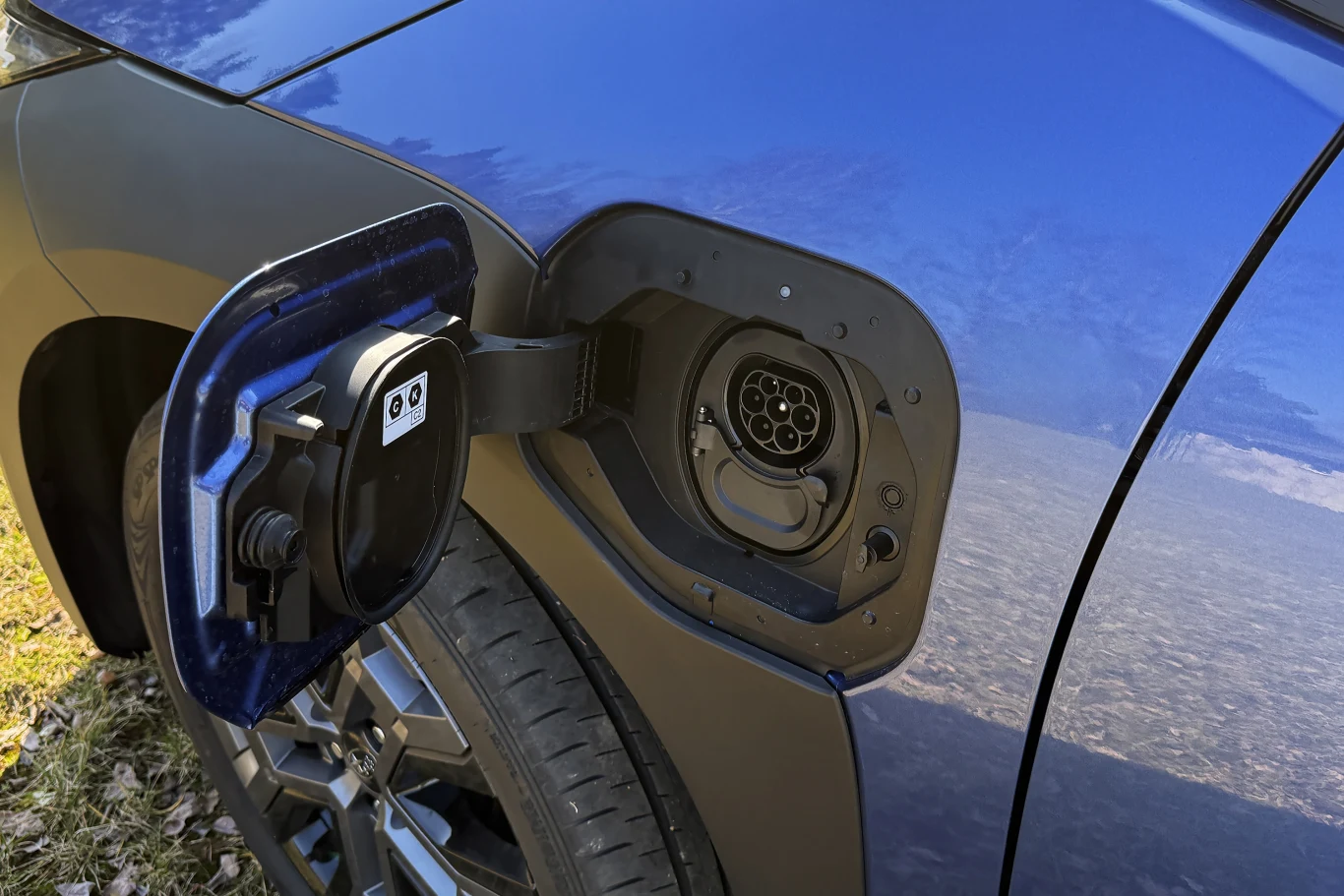 gniazdo ładowania samochodu elektrycznego umieszczone w błotniku pojazdu, widoczne klapka ochronna oraz charakterystyczny port do podłączenia kabla