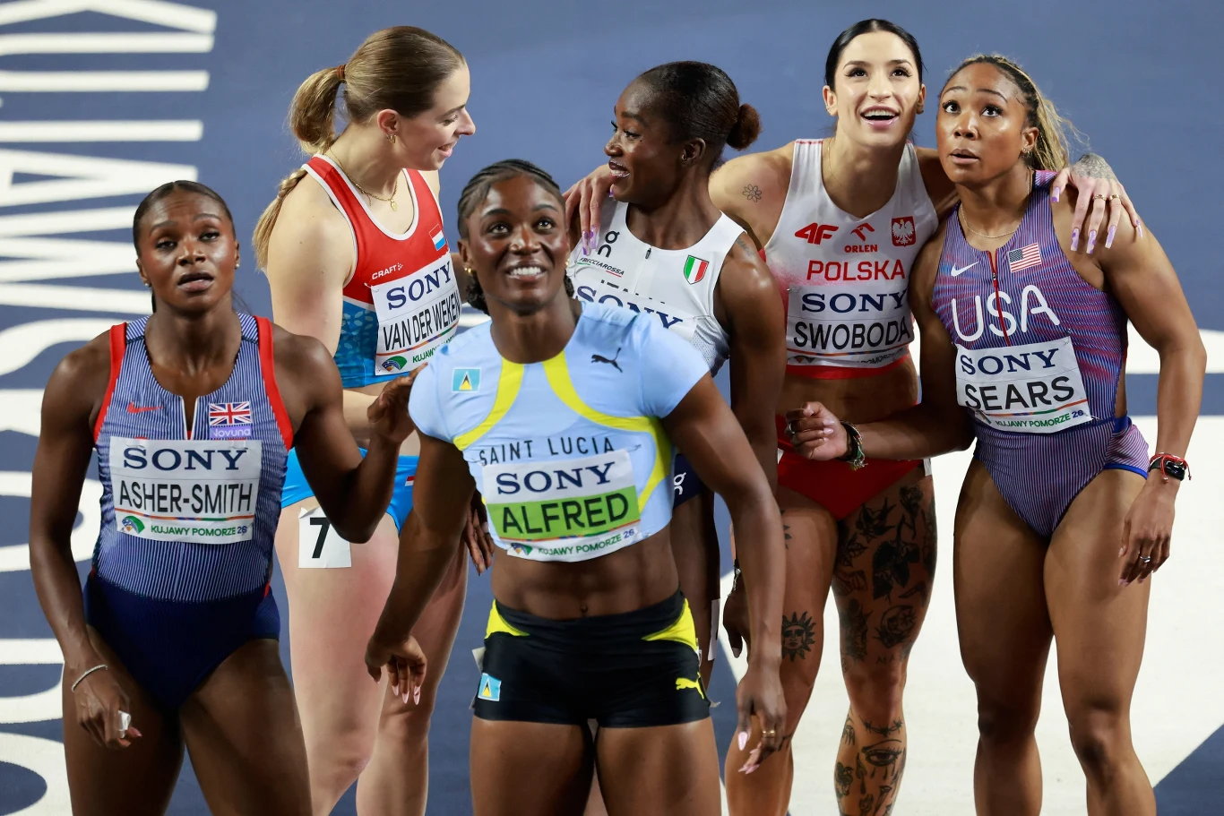Sześć zawodniczek lekkoatletycznych ubranych w stroje narodowe i startowe stojących razem na bieżni, skupionych i patrzących w górę, uśmiechających się i rozmawiających po zakończonym biegu.