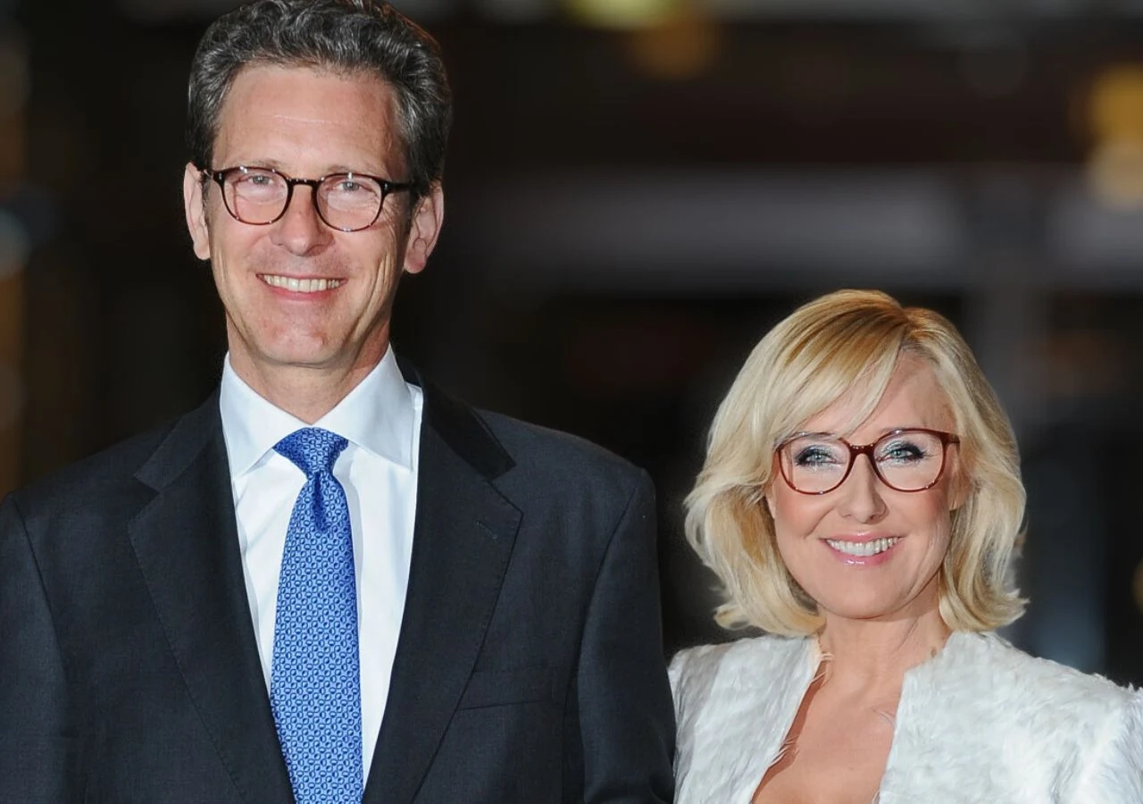 Przemysław Schmidt i Agata Młynarska w 2014 roku Elegancko ubrana para, mężczyzna w garniturze i krawacie oraz kobieta w białej marynarce z okularami, oboje uśmiechnięci i patrzący w stronę obiektywu.