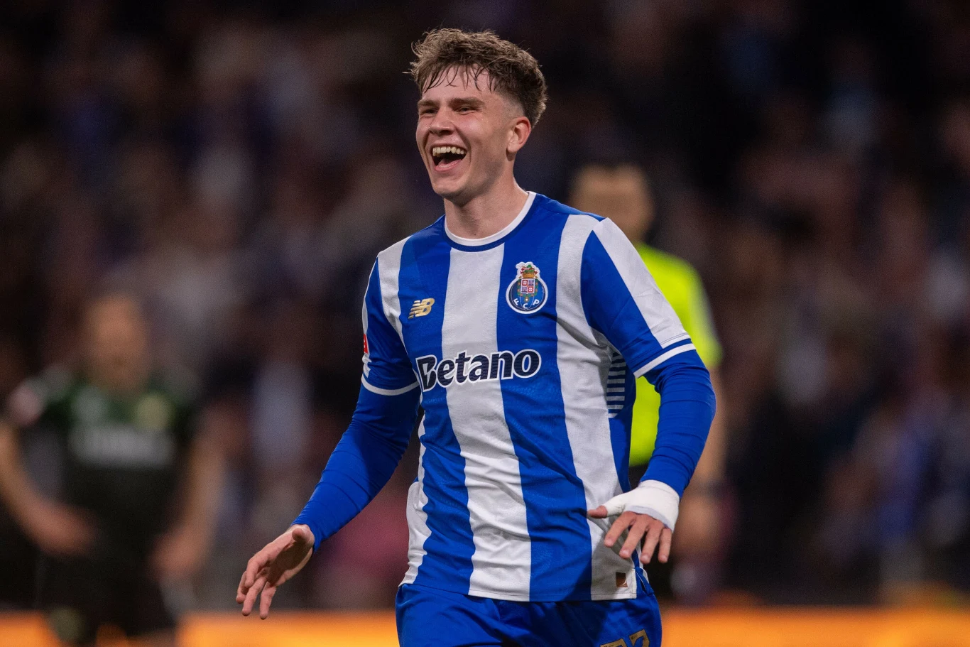 piłkarz w niebiesko-białej koszulce FC Porto z szerokim uśmiechem na twarzy biega po boisku podczas meczu, z wyraźnie widocznymi emocjami radości po zdobyciu bramki