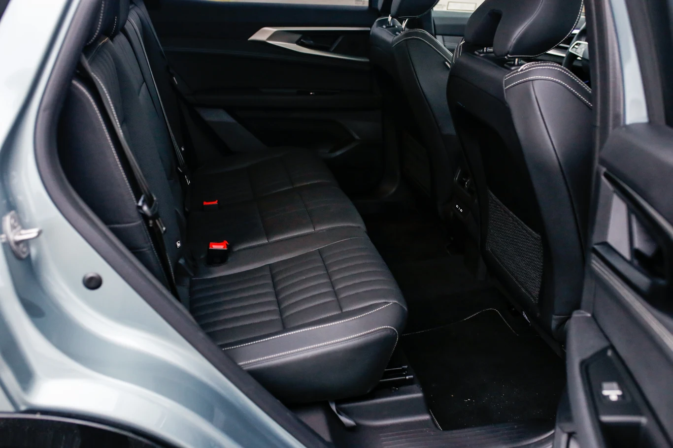 czarne skórzane tylne siedzenia samochodu z przeszyciami, widoczne dwa zaczepy ISOFIX i przestronne miejsce na nogi, nowoczesne wykończenia boczków drzwi