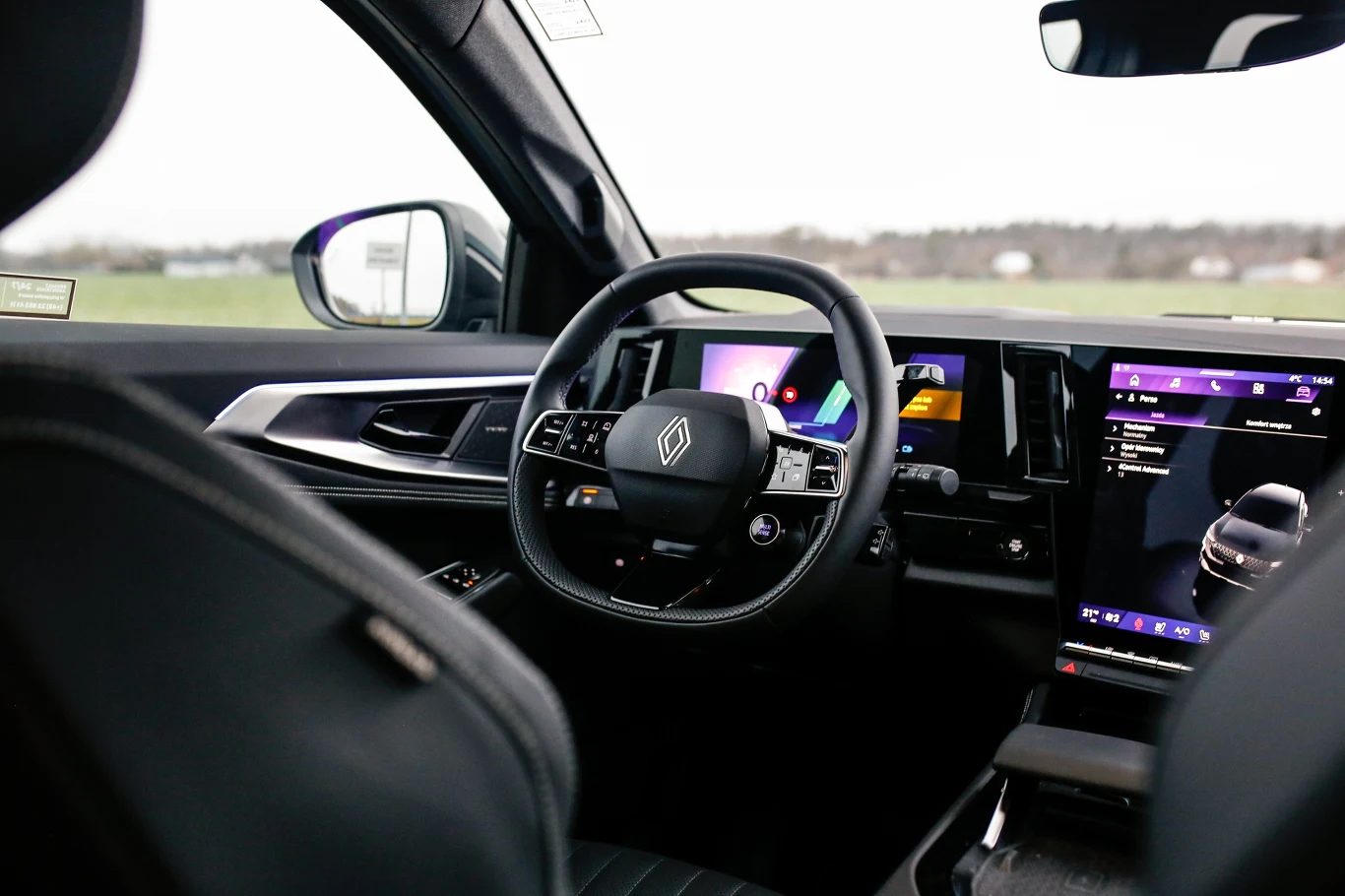 nowoczesne wnętrze samochodu Renault z cyfrowym kokpitem, dużym panelem multimedialnym po prawej stronie kierownicy oraz sportową, wielofunkcyjną kierownicą ozdobioną logo marki