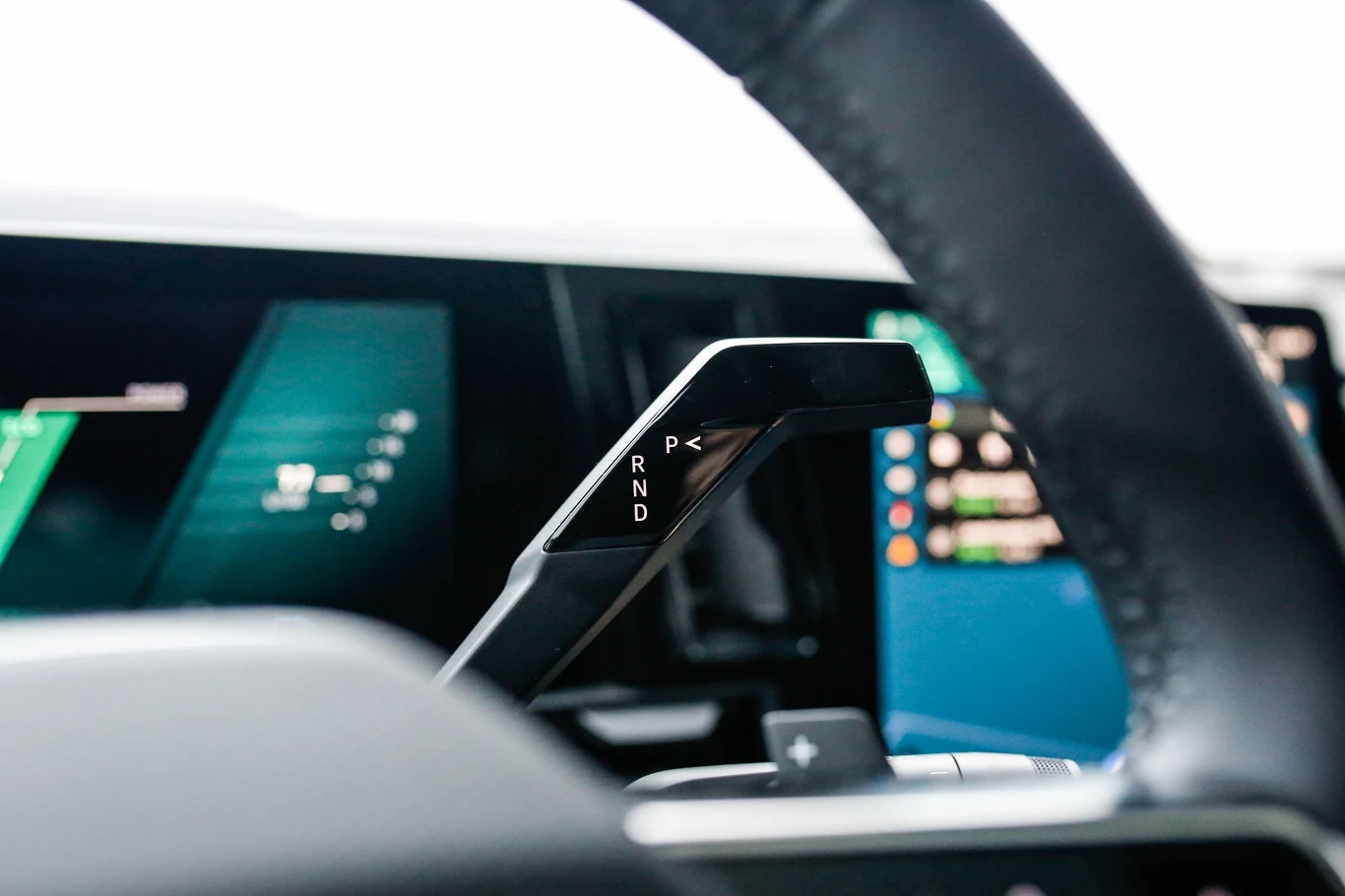 dźwignia zmiany biegów automatycznej skrzyni biegów z widocznym oznaczeniem pozycji P, R, N, D umieszczona w nowoczesnym wnętrzu samochodu z elektronicznymi wyświetlaczami na desce rozdzielczej