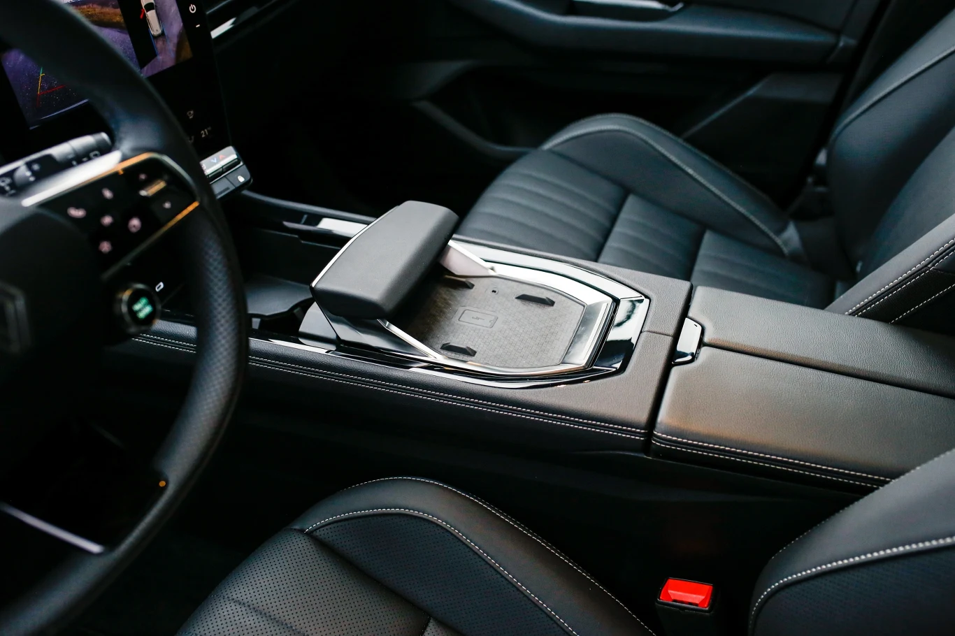 nowoczesna konsola centralna samochodu z panelem dotykowym, skórzanymi siedzeniami i przeszyciami w jasnym kolorze, wyraźnym podłokietnikiem oraz dużym ekranem multimedialnym po lewej stronie