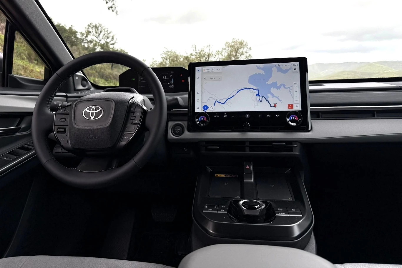 nowoczesna deska rozdzielcza samochodu Toyota z dużym, poziomym ekranem nawigacji, ergonomicznie rozmieszczonymi przyciskami, cyfrowym panelem sterowania oraz kompaktową kierownicą z logo marki
