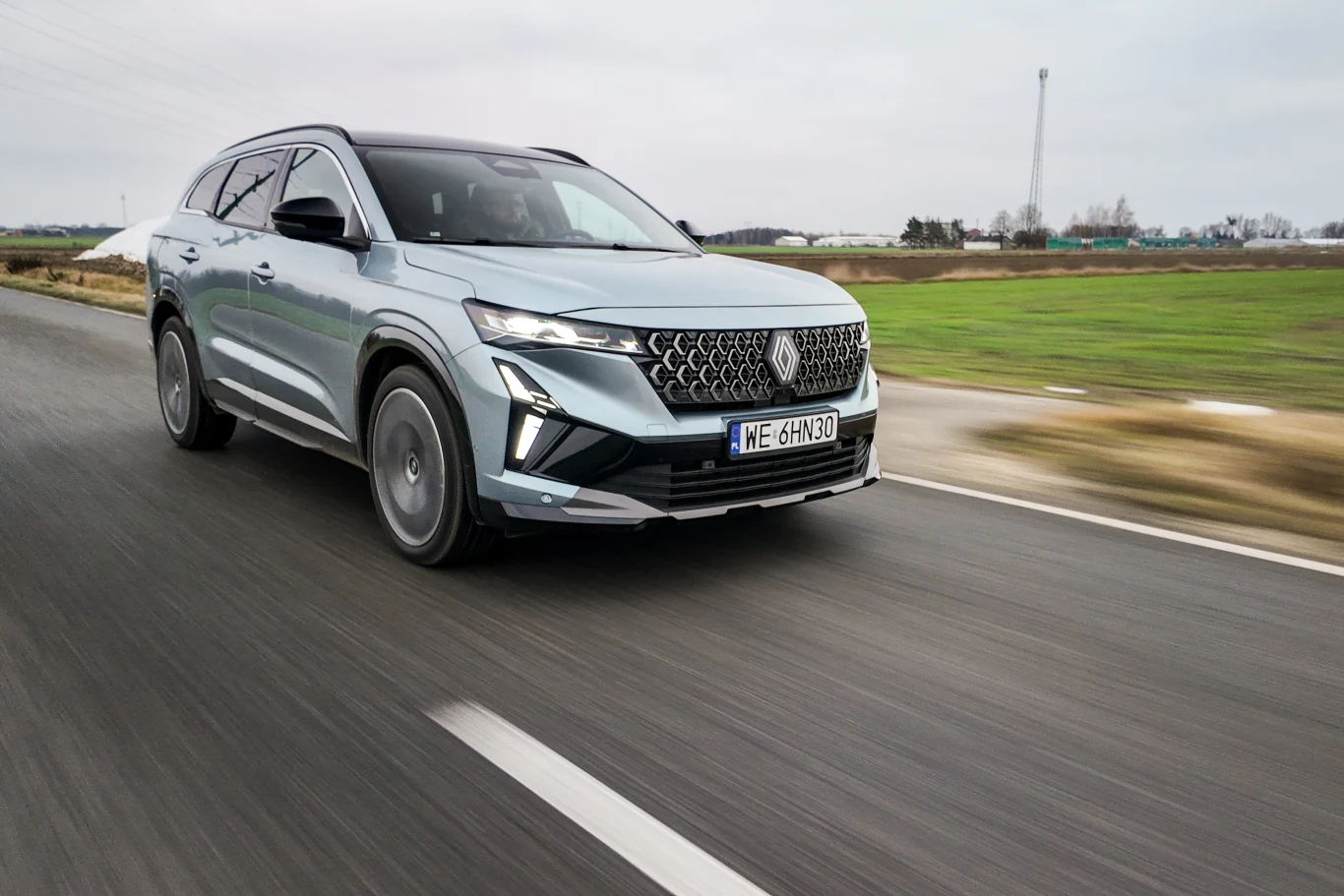 srebrny SUV poruszający się z dużą prędkością po asfaltowej drodze, na pierwszym planie jego dynamiczna i nowoczesna sylwetka z charakterystycznym grillem oraz wyrazistym wzorem świateł LED