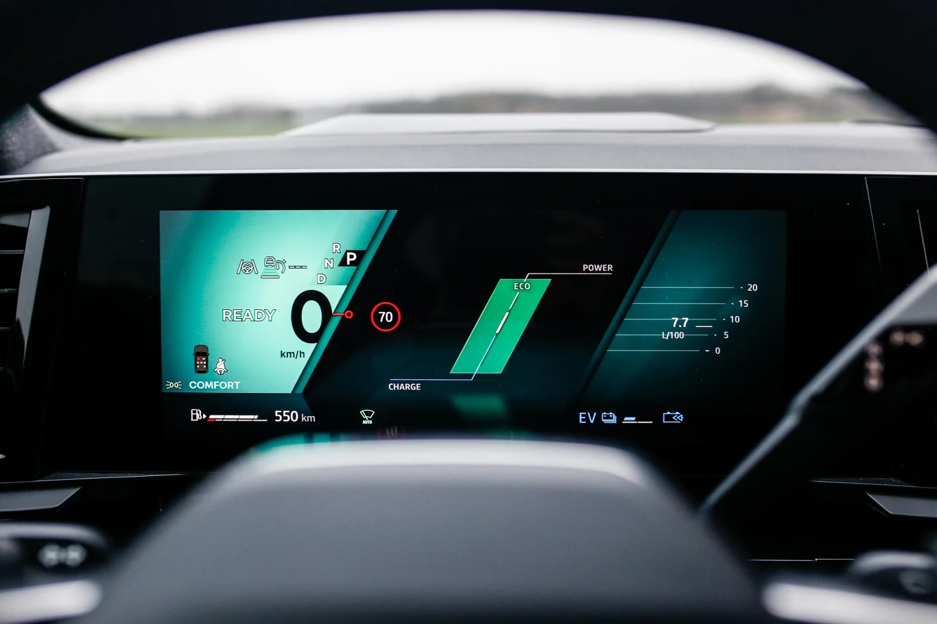 Cyfrowy wyświetlacz kokpitu samochodu prezentujący prędkość, aktywny tryb jazdy, wskazania nawigacji oraz poziom naładowania baterii i zasięg pojazdu.