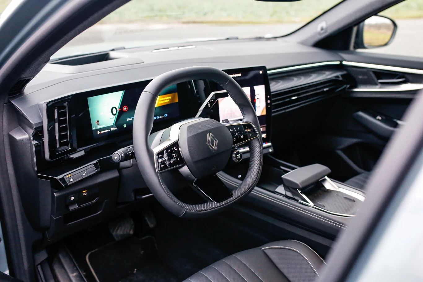 nowoczesne wnętrze samochodu z cyfrowym kokpitem, dużym ekranem dotykowym na konsoli centralnej oraz wielofunkcyjną kierownicą, czarne skórzane fotele i minimalistyczny design