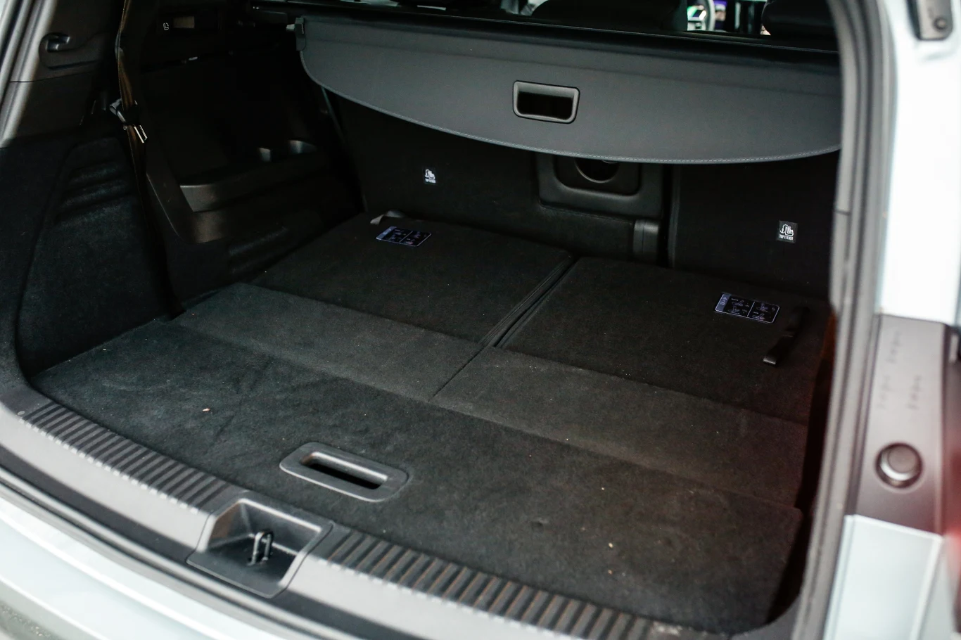 duży, płaski bagażnik samochodu z rozłożonymi tylnymi siedzeniami, pokryty czarną wykładziną