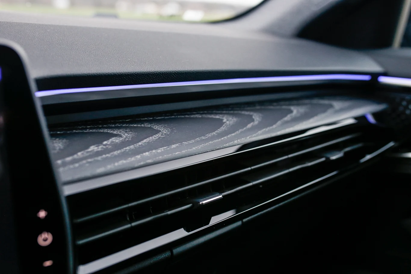 kokpit samochodu z nowoczesnym podświetleniem LED oraz dekoracyjną listwą z geometrycznym wzorem nad wyprofilowanymi kratkami nawiewu