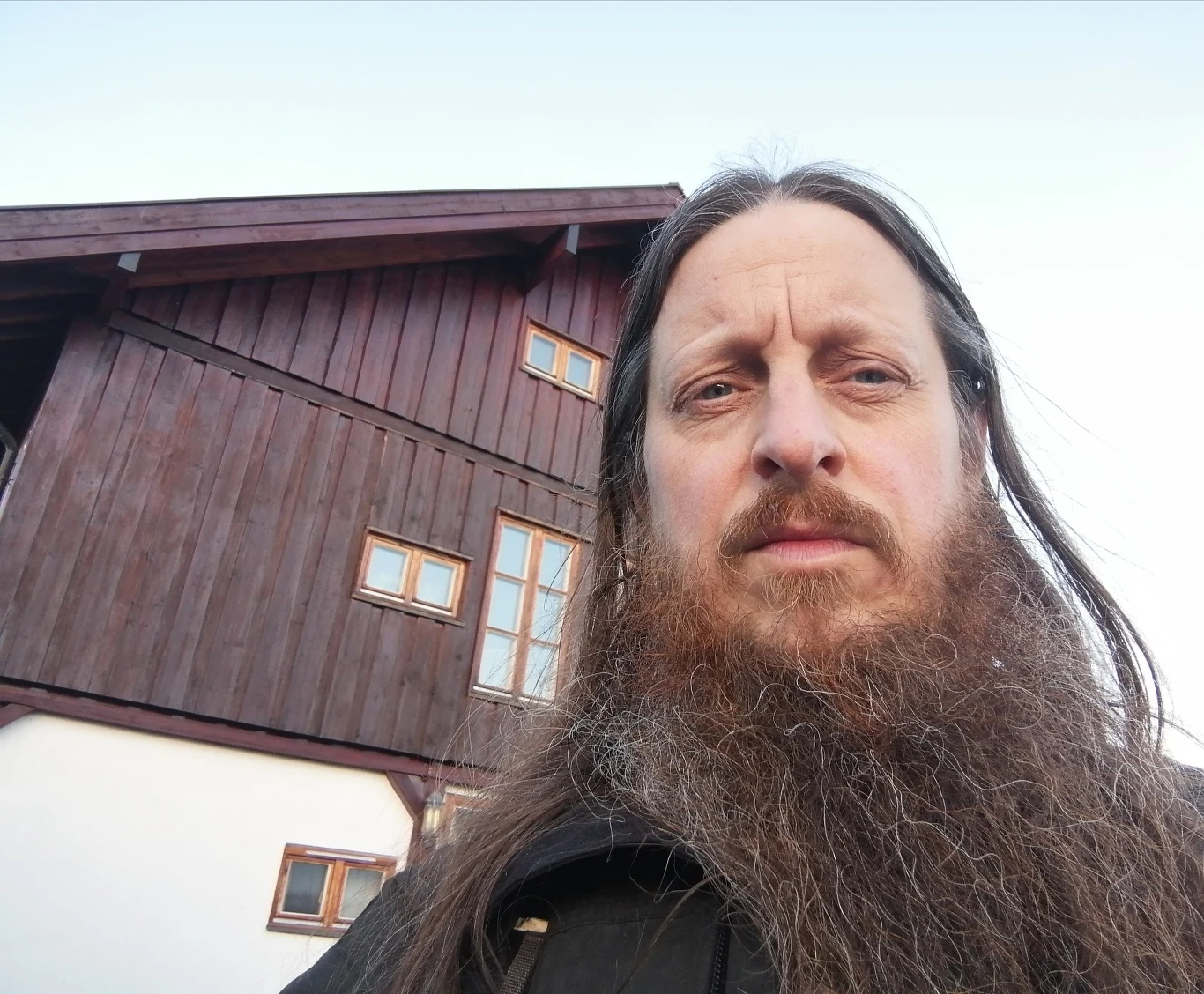Fenriz ujawnia szczegóły nowej płyty Darkthrone Fenriz z długą brodą i włosami przed drewnianym budynkiem z kilkoma oknami