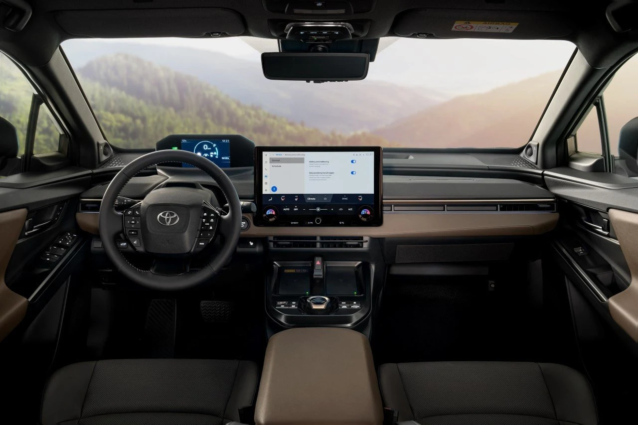 nowoczesne wnętrze samochodu marki Toyota z dużym ekranem dotykowym na desce rozdzielczej, cyfrowym zestawem wskaźników za kierownicą oraz dwukolorową tapicerką foteli i deski rozdzielczej