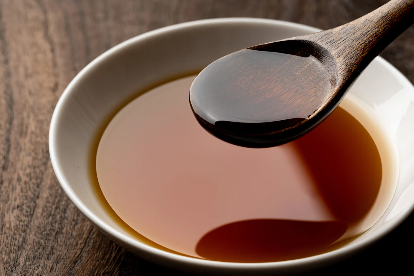 Ten zapomniany olej ma wysoką zawartość kwasów omega-3 i omega-6. Drewniana łyżka zanurzona w miseczce z ciemnym olejem rydzowym na drewnianej powierzchni.