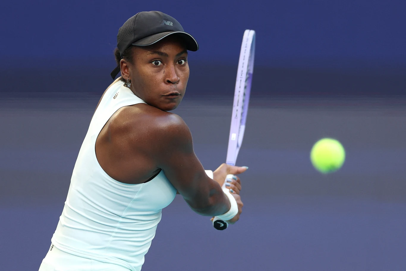 Coco Gauff tenisistka w jasnym stroju i czarnej czapce skupiona na odbiciu piłki rakietą podczas meczu