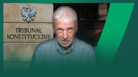 mężczyzna o siwych włosach i brodzie stoi na tle tablicy z napisem 'Trybunał Konstytucyjny' oraz godłem Polski