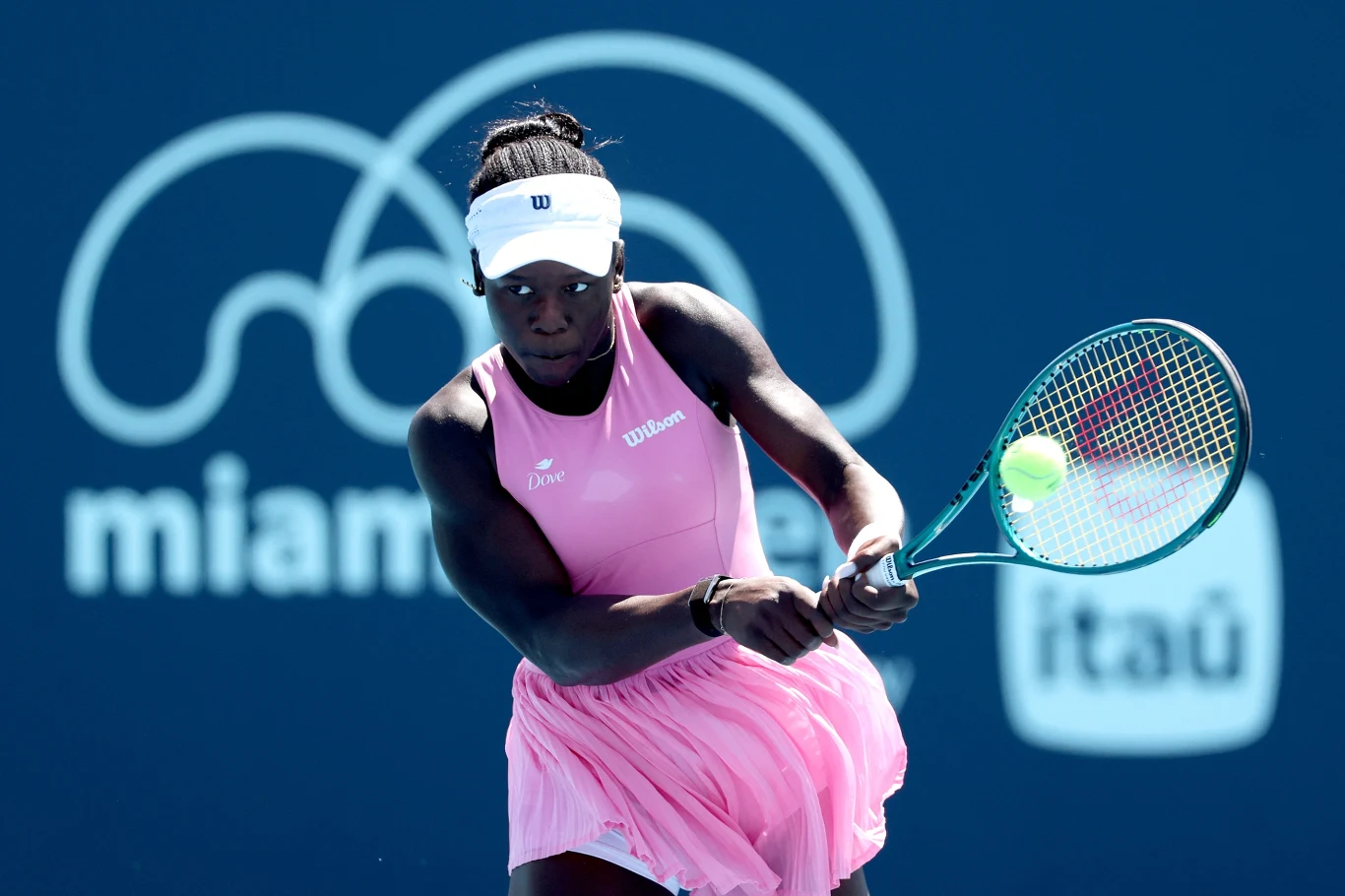 tenisistka w różowej sukience koncentruje się podczas uderzenia piłki rakietą na tle niebieskiego kortu z widocznym logo turnieju Miami Open