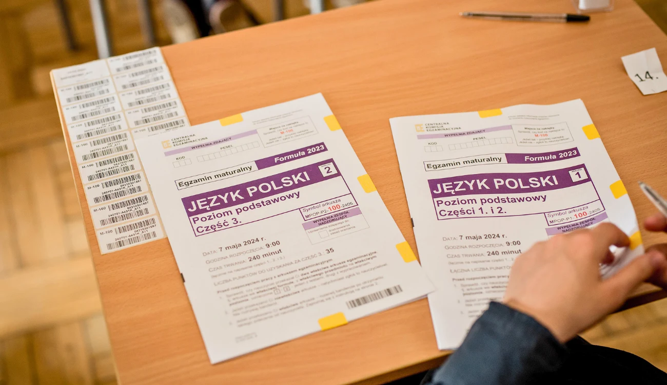 Kiedy można unieważnić egzamin maturalny? Arkusze egzaminu maturalnego z języka polskiego, długopis, naklejki na drewnianym biurku.