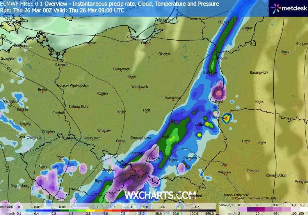 Mapa pogodowa Polski z wyraźnym pasem intensywnych opadów rozciągającym się od południowego zachodu na północny wschód, obejmującym miasta takie jak Łódź, Warszawa i Bydgoszcz; kolory wskazujące różne natężenie opadów, największe w centralnej części kr...