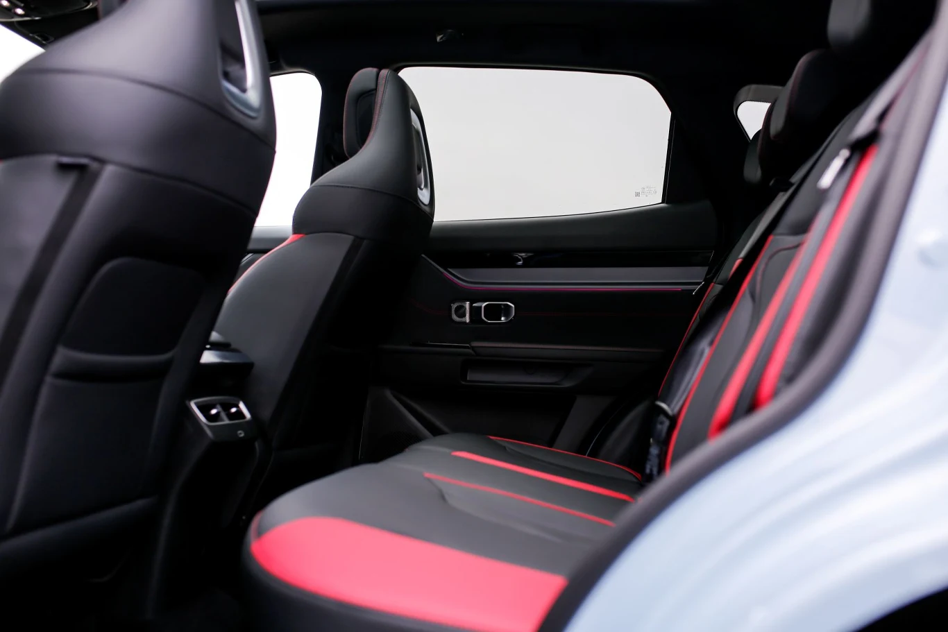 tylne siedzenia samochodu z czarną tapicerką i czerwonymi wstawkami, przestronne wnętrze, sportowy wygląd foteli
