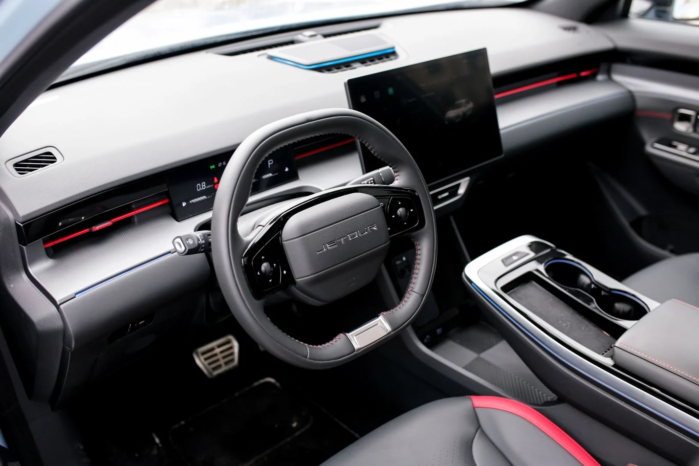 nowoczesne wnętrze samochodu z dużym, dotykowym ekranem centralnym, cyfrowym zestawem wskaźników oraz wielofunkcyjną kierownicą, podkreślone przez akcenty LED i eleganckie wykończenia tapicerki