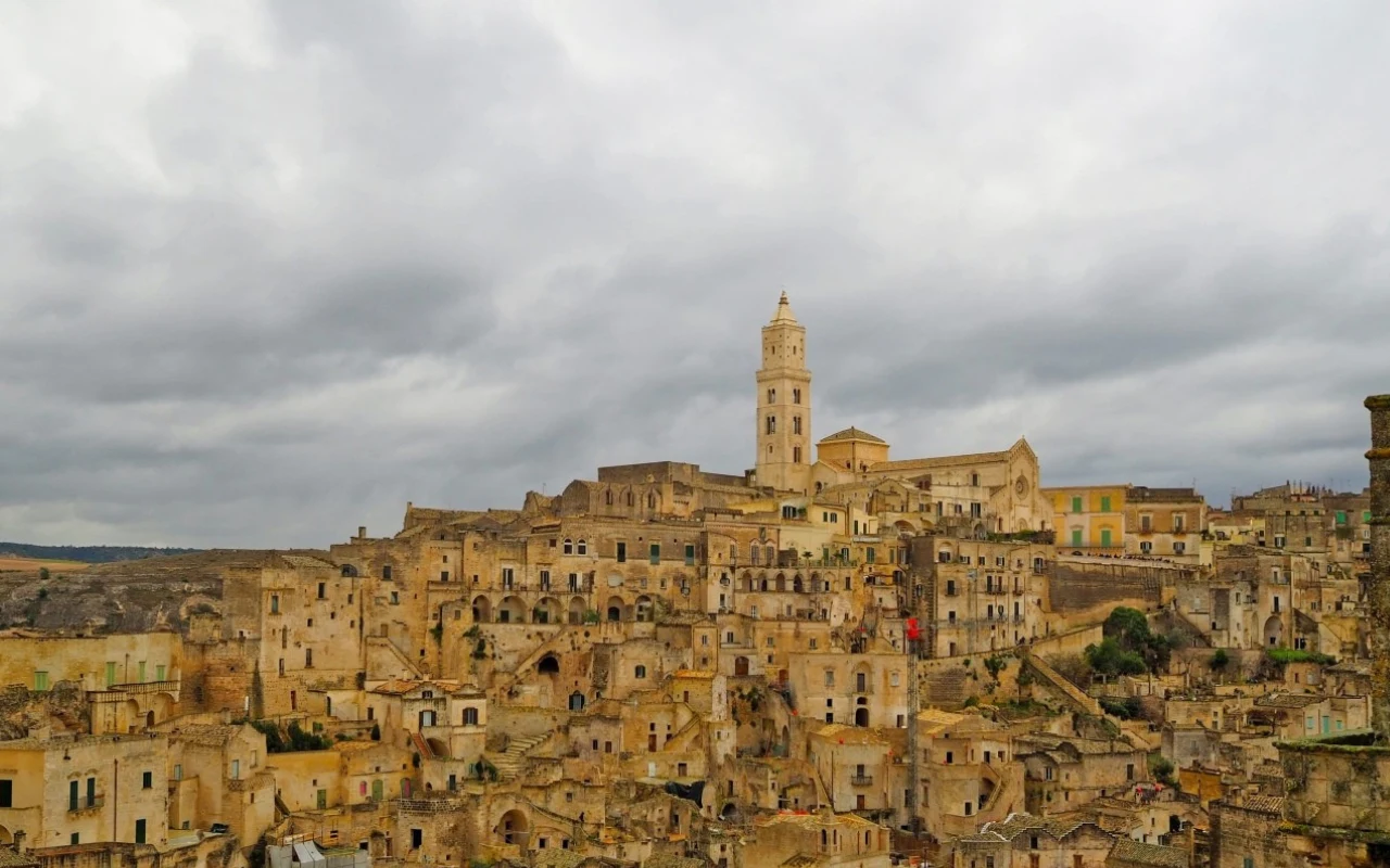 kamienne, historyczne budynki tworzące gęstą zabudowę na wzgórzu z dominującą wysoką wieżą kościelną pośrodku pod pochmurnym niebem