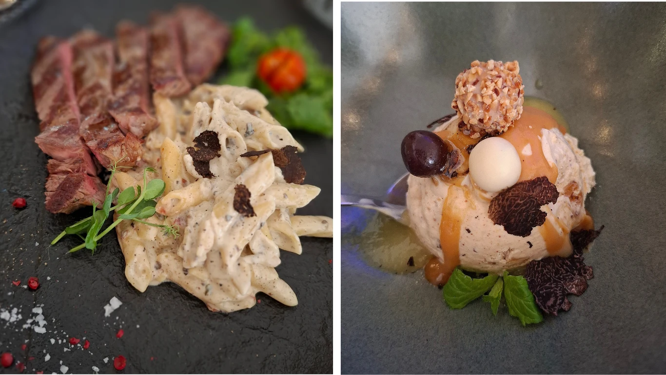Po lewej stronie talerza plastry grillowanego mięsa z kremowym makaronem penne, udekorowanym listkami ziół i czarnymi truflami, obok soczysta pomidorkowa dekoracja; po prawej stronie deser z lodami, polewą karmelową, kulką białej czekolady, winogronami...