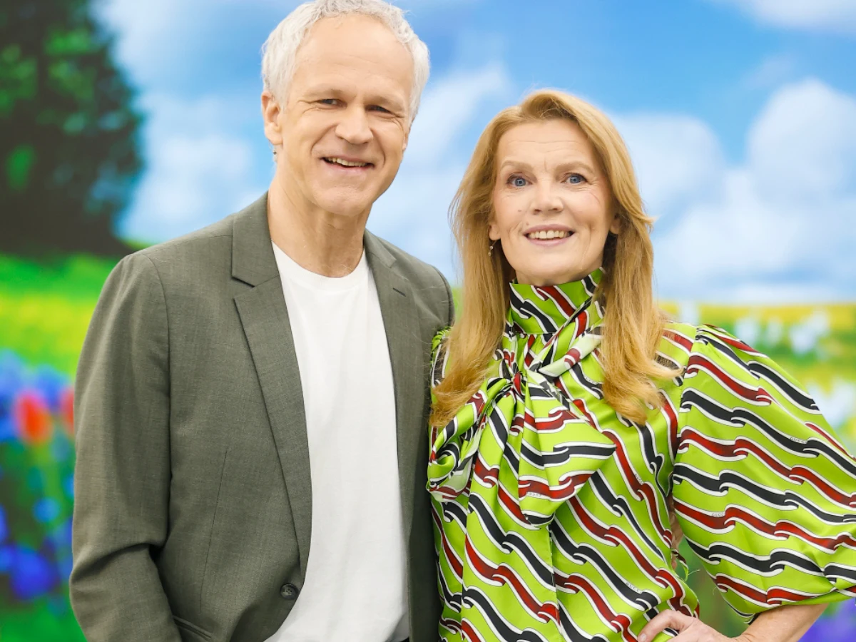 Radosław Pazura i Dorota Chotecka Radosław Pazura w szarej marynarce i Dorota Chotecka w kolorowej bluzce na tle łąki i nieba z chmurami