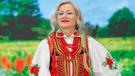 Beata Gurzyńska w tradycyjnym stroju ludowym, z czerwonymi koralami, uśmiecha się w studiu "halo tu polsat".