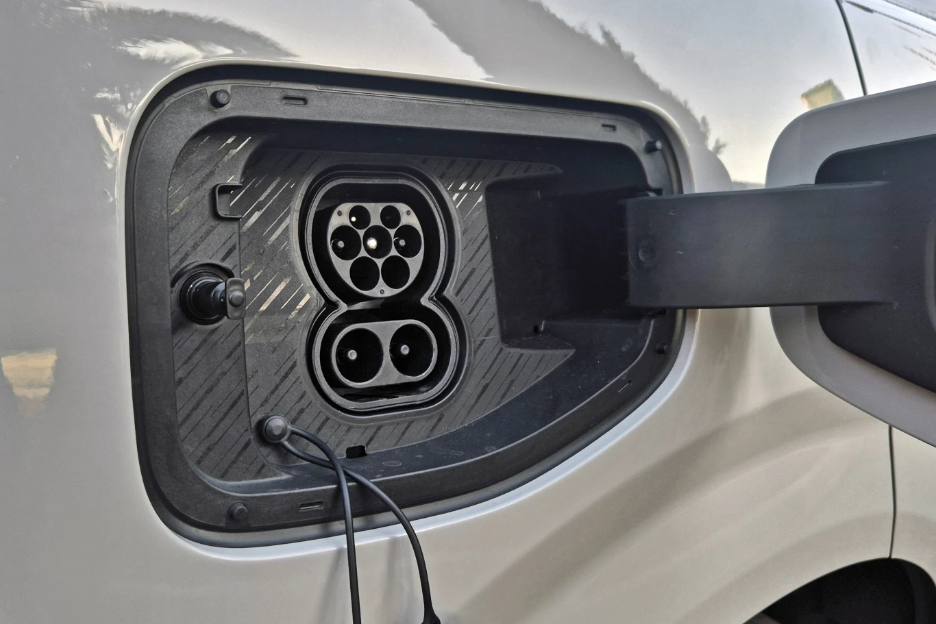 gniazdo ładowania samochodu elektrycznego z widocznym portem do podłączenia kabla, osadzone w karoserii pojazdu